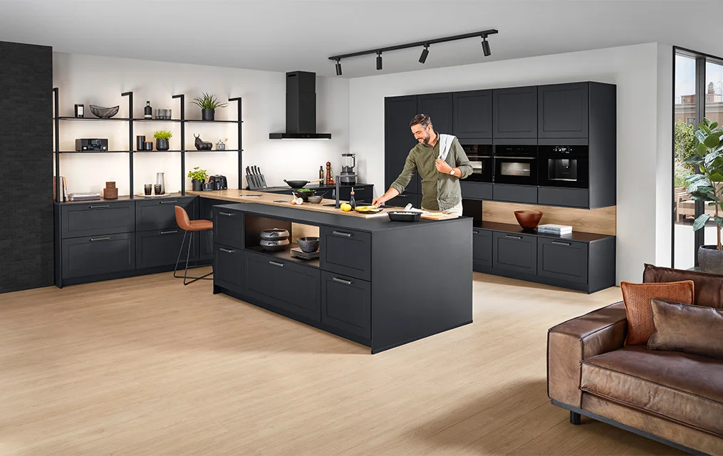 Mann beim Kochen in eleganter dunkler Nobilia Landhausküche